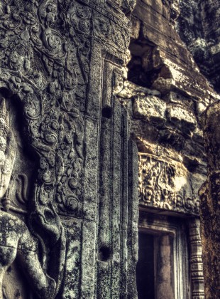 A carved sandstone apsara gazes down upon the millenia of ruin around her at the Bayon, Siem Reap.