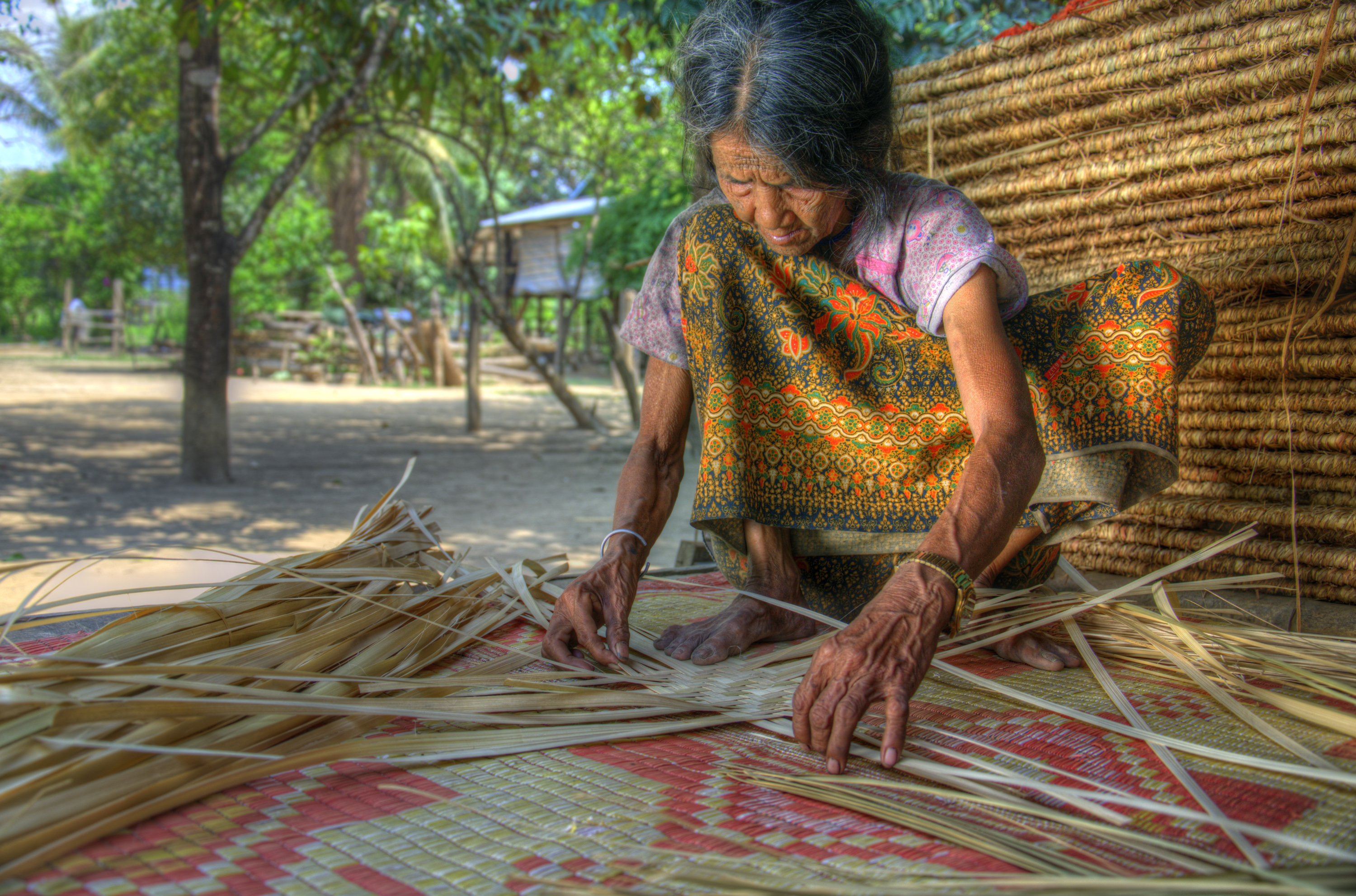 Hilltribe Brao woman weaving a sleeping mat by hand