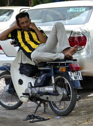 talking and riding; a moped driver in Phnom Penh, Camboja