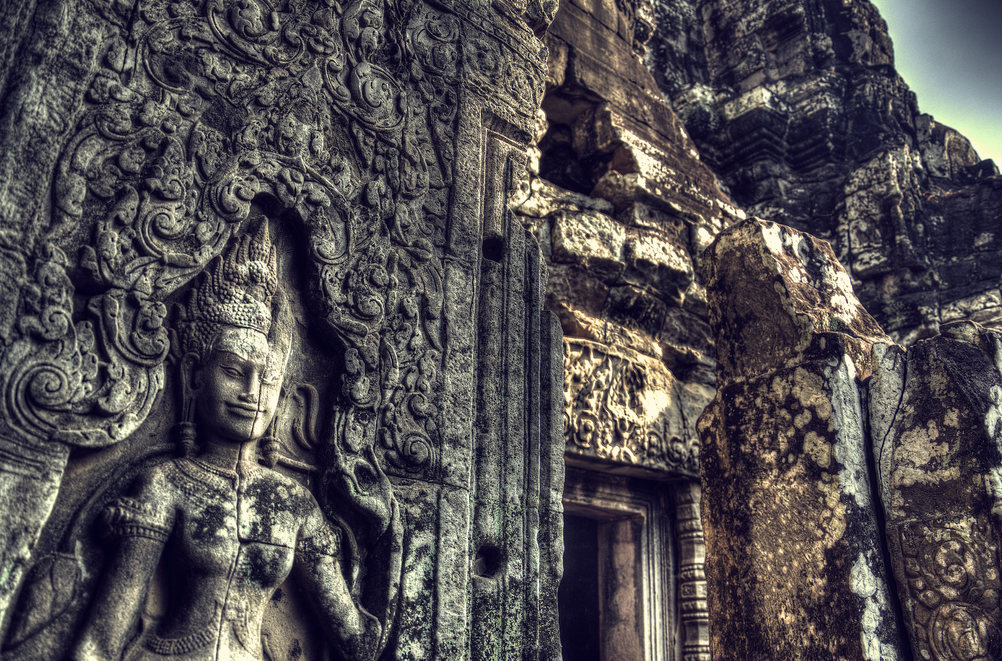 A carved sandstone apsara gazes down upon the millenia of ruin around her at the Bayon, Siem Reap.