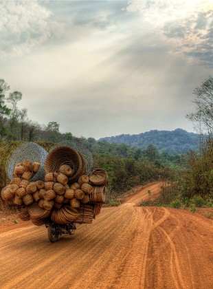 a cambodian itinerant seller of baskets, on a motorcycle