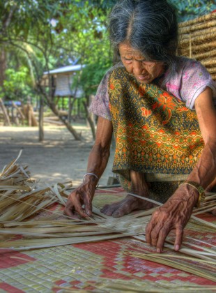 Hilltribe Brao woman weaving a sleeping mat by hand
